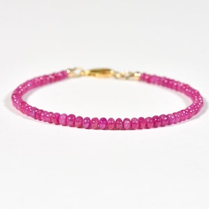 May include: A delicate pink gemstone bracelet with a gold clasp. The bracelet is made of small, round beads.