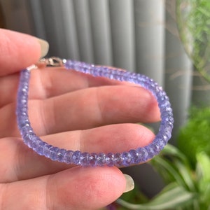 May include: A delicate bracelet made with small, faceted amethyst beads. The beads are a light purple color and are strung on a silver chain.