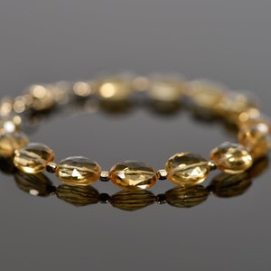 May include: A gold bracelet with oval-shaped, faceted, amber-colored beads.