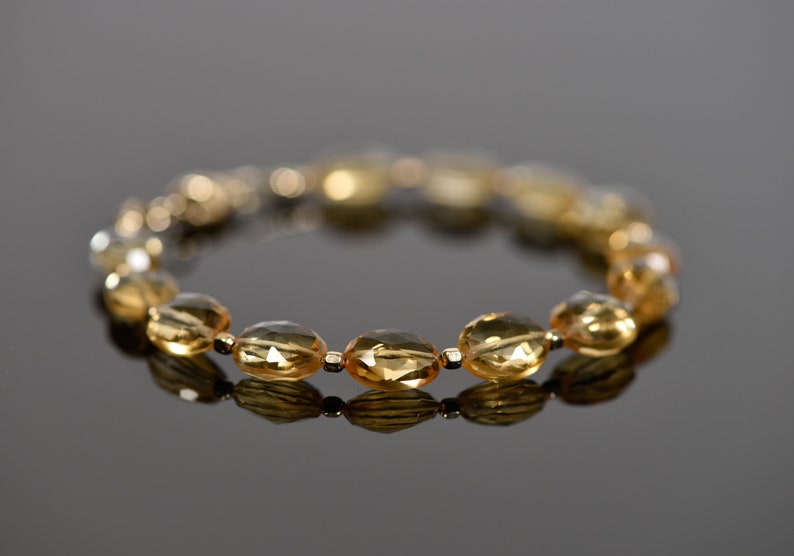 May include: A gold bracelet with oval-shaped, faceted, amber-colored beads.