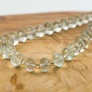 May include: A necklace made of light green faceted beads with gold accents. The beads are strung on a thin gold chain.