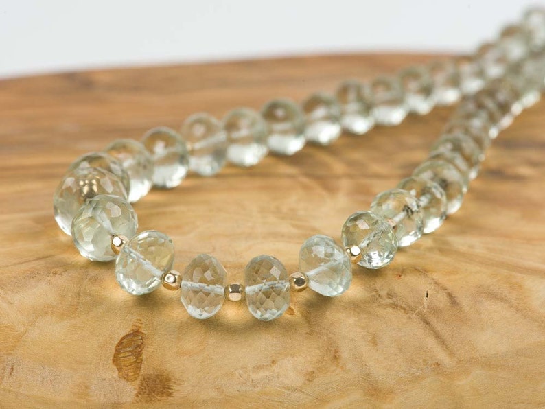 May include: A necklace made of light green faceted beads with gold accents. The beads are strung on a thin gold chain.