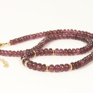 Puede incluir: Un collar hecho de peque&ntilde;as piedras preciosas redondas de color p&uacute;rpura con detalles dorados. El collar est&aacute; hecho de una cadena de cuentas con un cierre.