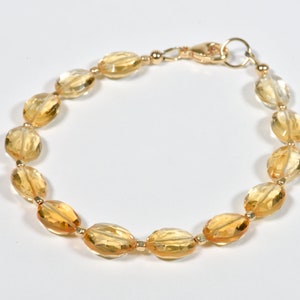 May include: A gold bracelet with oval-shaped citrine gemstones. The bracelet has a lobster clasp closure.