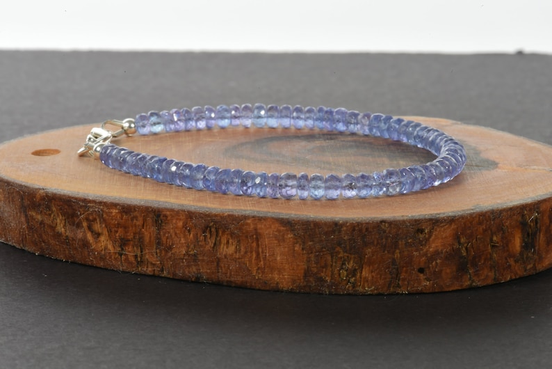 May include: A delicate bracelet made with small, light blue gemstone beads. The bracelet is strung on a silver chain and has a clasp closure.