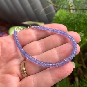 May include: A delicate bracelet made with small, faceted amethyst beads. The bracelet is strung on a silver chain with a lobster clasp.