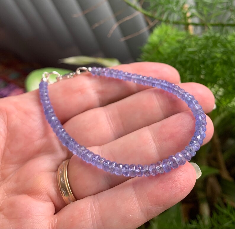 May include: A delicate bracelet made with small, faceted amethyst beads. The bracelet is strung on a silver chain with a lobster clasp.
