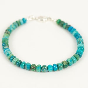 May include: A turquoise and green gemstone beaded bracelet with a silver clasp.