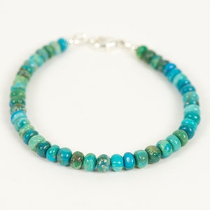 May include: A turquoise and green gemstone beaded bracelet with a silver clasp.
