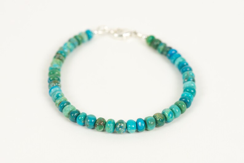 May include: A turquoise and green gemstone beaded bracelet with a silver clasp.