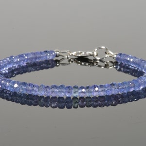May include: A delicate bracelet made with small, faceted, light blue gemstones. The bracelet has a silver clasp.