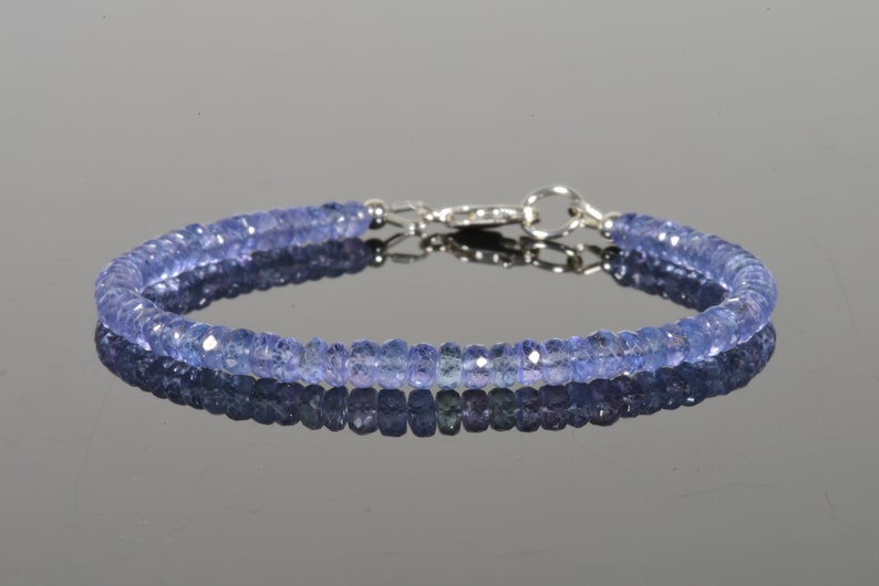 May include: A delicate bracelet made with small, faceted, light blue gemstones. The bracelet has a silver clasp.