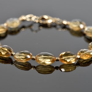 May include: A gold bracelet with oval-shaped topaz gemstones. The bracelet is made of gold and has a clasp closure.