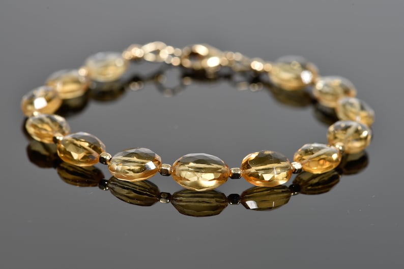May include: A gold bracelet with oval-shaped topaz gemstones. The bracelet is made of gold and has a clasp closure.