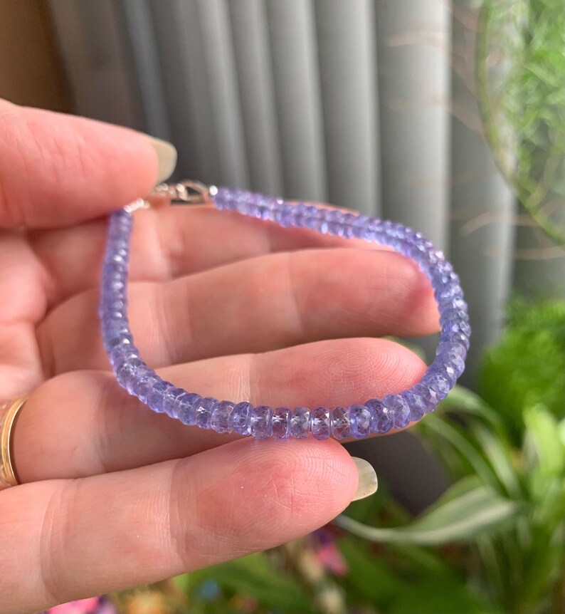 May include: A delicate bracelet made with small, faceted amethyst beads. The beads are a light purple color and are strung on a silver chain.