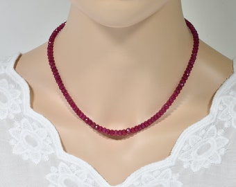 May include: A necklace made of small, faceted ruby beads. The necklace is on a mannequin wearing a white blouse.