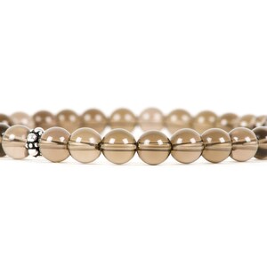Peut inclure: Un bracelet en perles de quartz fum&eacute; brun avec un accent de perle argent&eacute;e.