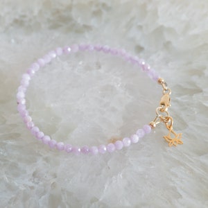 Peut inclure: Un bracelet d&eacute;licat compos&eacute; de perles violettes claires et d'un charme de lotus en or.