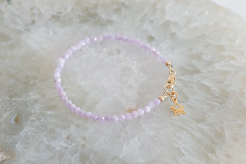 Peut inclure: Un bracelet d&eacute;licat compos&eacute; de perles violettes claires et d'un charme de lotus en or.