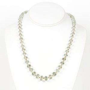 May include: A delicate necklace made of light green faceted beads strung on a gold chain.