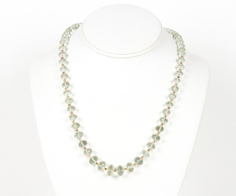 May include: A delicate necklace made of light green faceted beads strung on a gold chain.