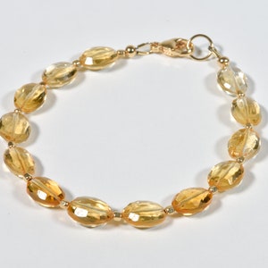May include: A gold bracelet with oval-shaped, faceted citrine gemstones. The bracelet has a lobster claw clasp.