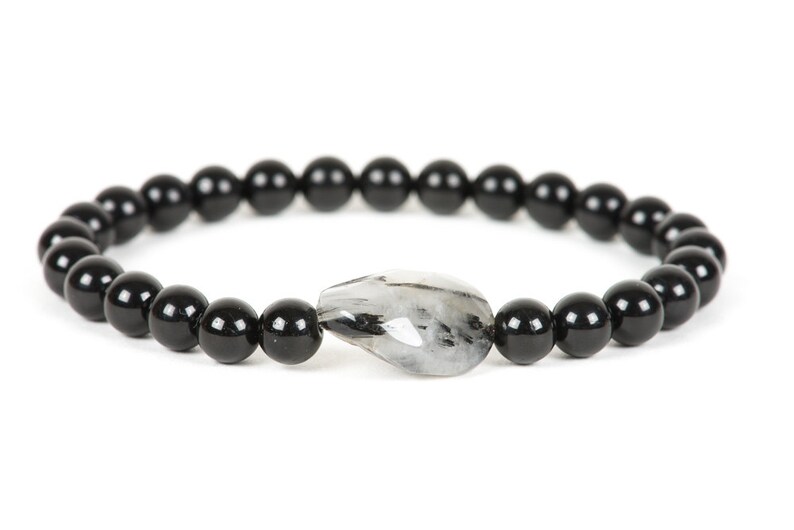 May include: A black beaded bracelet with a single clear and grey gemstone charm.
