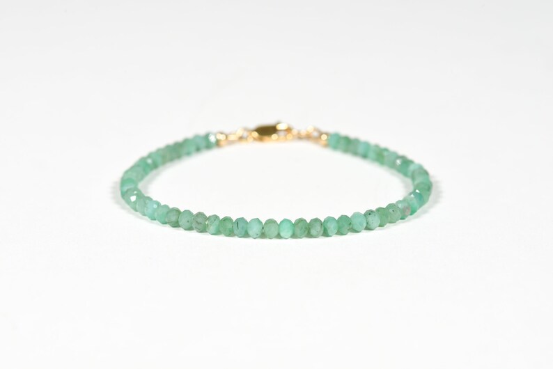 Op de afbeelding: Een delicate armband van groene edelstenen met een gouden sluiting. De armband is gemaakt van kleine, gefacetteerde kralen.