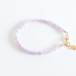 Peut inclure: Un bracelet d&eacute;licat compos&eacute; de petites perles de couleur lilas clair et d'un fermoir en or avec un pendentif en forme de fleur de lotus.