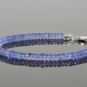 May include: A delicate bracelet made with small, faceted, light blue gemstones. The bracelet has a silver clasp.