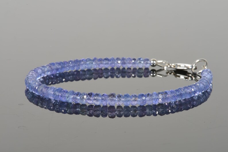 May include: A delicate bracelet made with small, faceted, light blue gemstones. The bracelet has a silver clasp.