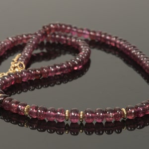 Puede incluir: Un collar largo hecho de peque&ntilde;as cuentas redondas de color p&uacute;rpura con detalles dorados. El collar est&aacute; hecho de piedras preciosas naturales y es una hermosa pieza de joyer&iacute;a.