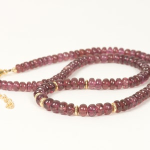 Puede incluir: Un collar de piedras preciosas rosas con detalles dorados. El collar est&aacute; hecho de peque&ntilde;as cuentas redondas y tiene un cierre de broche.