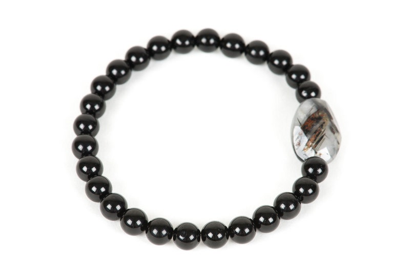 May include: Black beaded bracelet with a silver and black gemstone charm.
