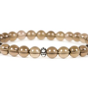Peut inclure: Un bracelet en pierres pr&eacute;cieuses brunes avec un accent de perle argent&eacute;e. Le bracelet est compos&eacute; de perles rondes et mesure environ 18 cm de long.