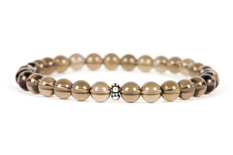 Peut inclure: Un bracelet en pierres pr&eacute;cieuses brunes avec un accent de perle argent&eacute;e. Le bracelet est compos&eacute; de perles rondes et mesure environ 18 cm de long.