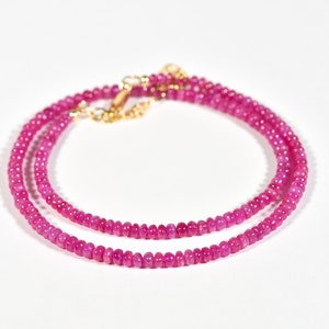 Könnte beinhalten: Eine doppelreihige Halskette aus rosafarbenen Edelsteinperlen mit einem goldenen Verschluss.