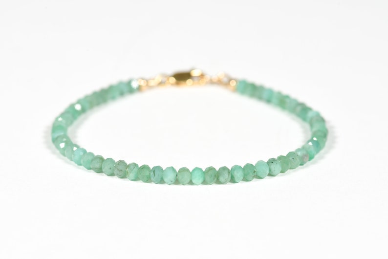 Op de afbeelding: Een delicate armband van groene edelstenen met een gouden sluiting. De armband is gemaakt van kleine, gefacetteerde kralen.