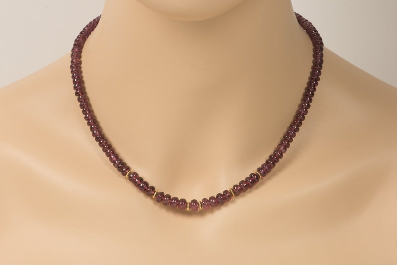Puede incluir: Un collar de piedras preciosas de color p&uacute;rpura con detalles dorados. El collar est&aacute; hecho de peque&ntilde;as cuentas redondas y mide aproximadamente 45 cent&iacute;metros de largo.