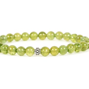 May include: A green gemstone bracelet with a silver bead accent. The bracelet is made of round beads and is approximately 7 inches in length.