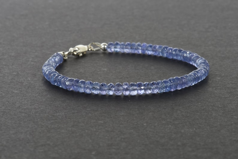 May include: A delicate blue gemstone bracelet with a silver clasp. The bracelet is made of small, round beads that are strung together to create a simple and elegant design.