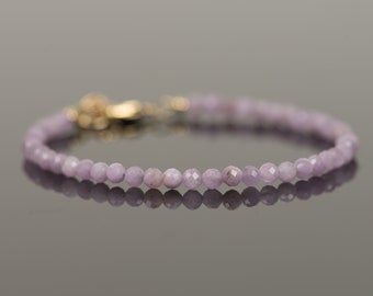 May include: A delicate bracelet made of light purple gemstone beads with a gold clasp.