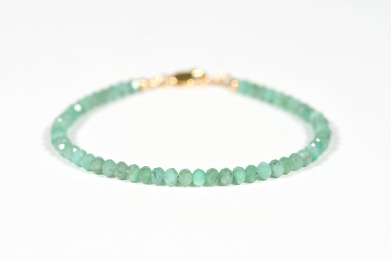 Op de afbeelding: Een delicate armband van groene edelstenen met een gouden sluiting. De armband is gemaakt van kleine, gefacetteerde kralen.