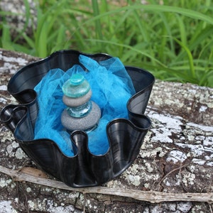 May include: A black vinyl record repurposed into a bowl with a blue tulle fabric and a stack of gray and blue stones in the center.