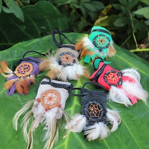 May include: Six small pouches with dreamcatcher designs and feathers. The pouches are in various colors, including green, purple, brown, beige, red, and black.