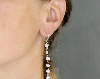 Puede incluir: Pendientes de aro de plata con una cadena colgante de perlas blancas.