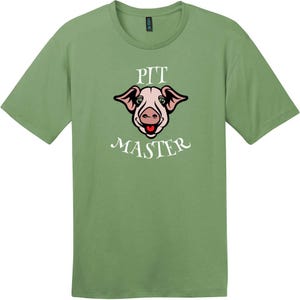 May include: A sage green short-sleeve t-shirt featuring a graphic of a pig's face in the center. Above the pig, the word PIT is printed in white, and below the pig, the word MASTER is printed in white. The pig has pink skin and a red tongue.