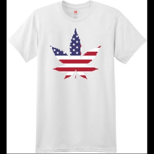 Op de afbeelding: Wit T-shirt met een marihuanabladontwerp. Het blad is gemaakt van de kleuren van de Amerikaanse vlag, rood, wit en blauw.