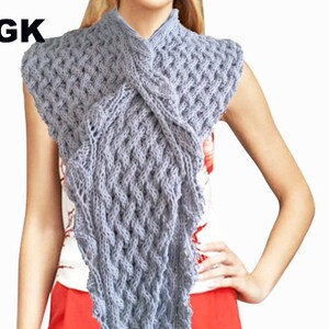 May include: A grey knitted scarf with a textured pattern. The scarf is draped around a person's neck and shoulders.