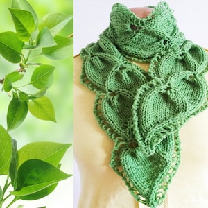 May include: A green knitted scarf with a leaf pattern. The scarf is made with a delicate stitch and has a lacy edge.